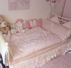 a small child's bed with stuffed animals on it and pink carpeted flooring