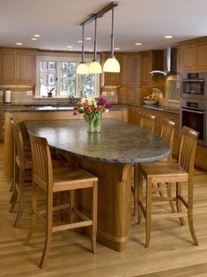 a large kitchen with wooden floors and an island in the middle, surrounded by chairs