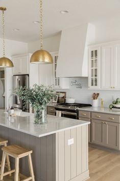 a large kitchen with an island and two stools in front of the counter top