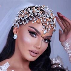 a woman wearing a bridal headpiece with pearls and jewels on her face,