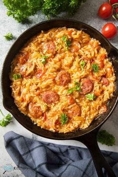 a skillet filled with pasta, sausage and parsley on top of a table