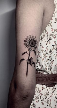 a woman's arm with a sunflower tattoo on it