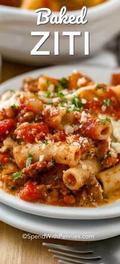 a white plate topped with pasta and meat covered in sauce on top of a wooden table