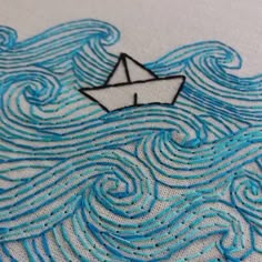 an embroidery pattern with a boat in the middle of it on a piece of fabric