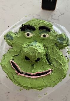 a cake with green frosting and a face on it