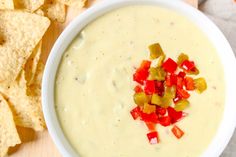 a white bowl filled with dip surrounded by tortilla chips