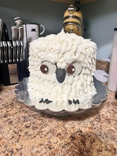 a cake that looks like an owl is on a counter with knives in the background