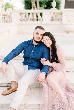 a man and woman are sitting on the steps together, posing for a photo with their arms around each other