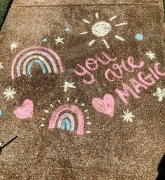 the sidewalk has chalk drawings on it with words and rainbows written in pink, blue, and green