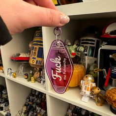 a hand holding a star wars keychain in front of shelves filled with toys