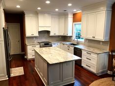 an empty kitchen with white cabinets and wood flooring in the middle of the room