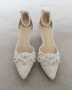 "Crochet style pointy toe heels with added small pearls applique and detachable ankle strap. Elegance and vintage inspired wear for your special day. DETAILS: HEELS: 3 inches COLORS AVAILABLE: Ivory and White UPPER: Synthetic upper and lining MATERIALS: Mandmade outsole ORIGIN: Imported STYLE NAME: EVA Not sure of which size to purchase? Shoes measurements are as follow: (Please note measurements taken the length of inside of shoe from toe to heel). Size 6 - 9.50\" Size 7 - 10.\" Size 8 - 10.25\ Pearl Wedding Shoes With Pointed Toe, Elegant Low Heel Wedding Shoes With Lace Trim, Elegant Wedding Heels With Lace Trim, Elegant Wedding Shoes With Lace Trim, Elegant Lace Wedding Shoes, Embellished Lace Wedding Shoes, Elegant Wedding Shoes With Lace Work, Pearl Embellished Closed Toe Wedding Shoes, Pearl Embellished Closed Toe Wedding Shoes For Ceremony