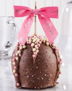 a chocolate cake with pink and white candies on it, tied to a wooden stick