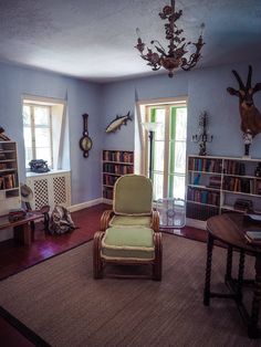 a living room filled with furniture and bookshelves covered in deer head mounted on the walls