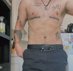 a shirtless man with tattoos on his chest standing in front of a book shelf