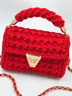 a red crocheted purse with a gold clasp on the handle and chain attached to it