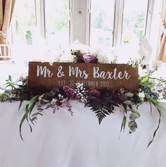 a wooden sign that says mr and mrs baxter on top of a table with flowers