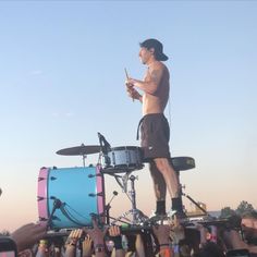 a man standing on top of a drum set in front of a group of people