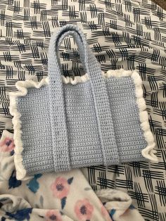 a crocheted purse sitting on top of a bed next to a flowery blanket