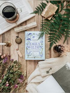 an open book sitting on top of a wooden table next to flowers and other items