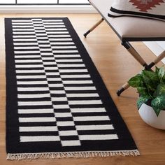 a black and white rug on the floor next to a chair with a potted plant