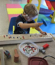 a young boy playing with an electronic device in a playroom filled with plastic toys