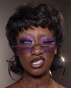 a woman with purple makeup and hoop earrings