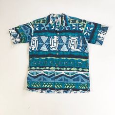 "1950's Hawaiian bark cloth shirt has a button front with silver Greek coin style buttons, and a chest pocket. Label is Andrade Resort Shops Waikiki. Made in Hawaii. Condition Excellent overall, has a faint small stain at the bottom of the pocket. Measurements Chest 44\" Waist 42\" Shoulder 18\" Sleeve length 10\" Length 28\" Best for a size medium." Retro Blue Button-up Hawaiian Shirt, Blue Retro Hawaiian Button-up Shirt, Blue Retro Button-up Camp Shirt, Retro Blue Button-up Camp Shirt, Cotton Button-up Hawaiian Shirt, Retro Button-up Hawaiian Shirt, Retro Blue Collared Hawaiian Shirt, Vintage Blue Cotton Camp Shirt, Vintage Cotton Collared Hawaiian Shirt