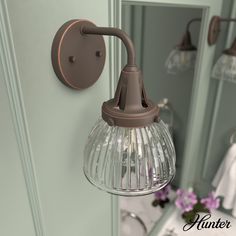 an old fashioned light fixture hangs from the side of a bathroom mirror next to a sink