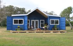 a small blue house sitting on top of a lush green field