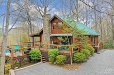 a log cabin in the woods surrounded by trees and shrubs, with a deck leading up to it