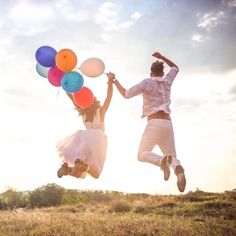 two people jumping up in the air with balloons on their feet and one person wearing white