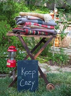 a sign sitting on top of a wooden stand in the grass next to a pile of blankets