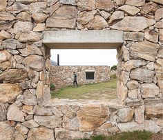 there is a man standing in the window of a stone wall that looks like it's made out of rocks