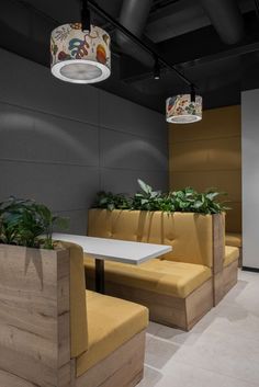 the interior of a restaurant with yellow booths and plants