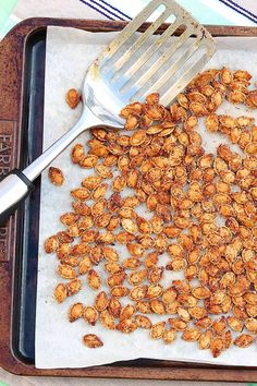 a tray filled with nuts and a spatula on top of it next to a fork