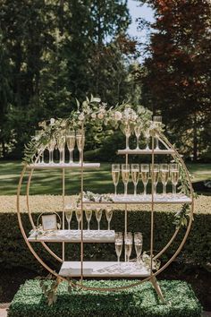 a table with champagne glasses on it and greenery in the background at a wedding