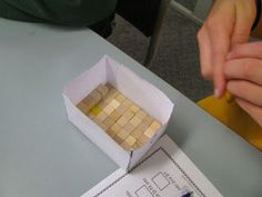 a person sitting at a table with some sort of food in a box on it