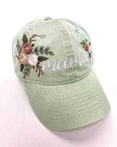 a baseball cap with embroidered flowers and the word mama on it, sitting against a white background