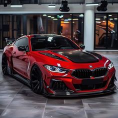 a red bmw sports car parked in front of a building with lights on the ceiling