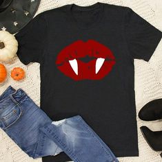 a t - shirt with red lips and fangs on it, next to pumpkins