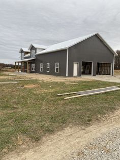 a large gray barn sitting on top of a grass covered field