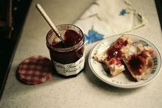 two pieces of pizza on a plate next to a jar of jam