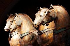 three wooden horses are standing next to each other in front of a black background with an arch