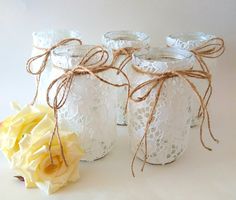 three mason jars with lace and twine tied around the lids are sitting next to a yellow rose