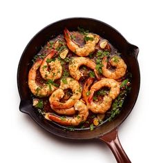 a skillet filled with cooked shrimp and garnished with parsley on the side