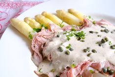 a white plate topped with meat covered in gravy next to french fries and green beans