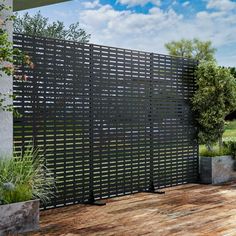 an outdoor area with wooden flooring and black privacy screens on the side of a house