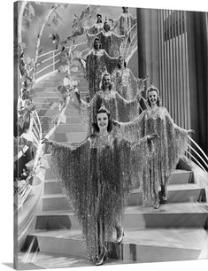 an old black and white photo of some women dressed in fringed outfits on stairs