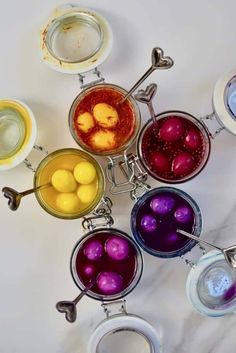 several bowls filled with different types of colored liquid and some spoons next to each other